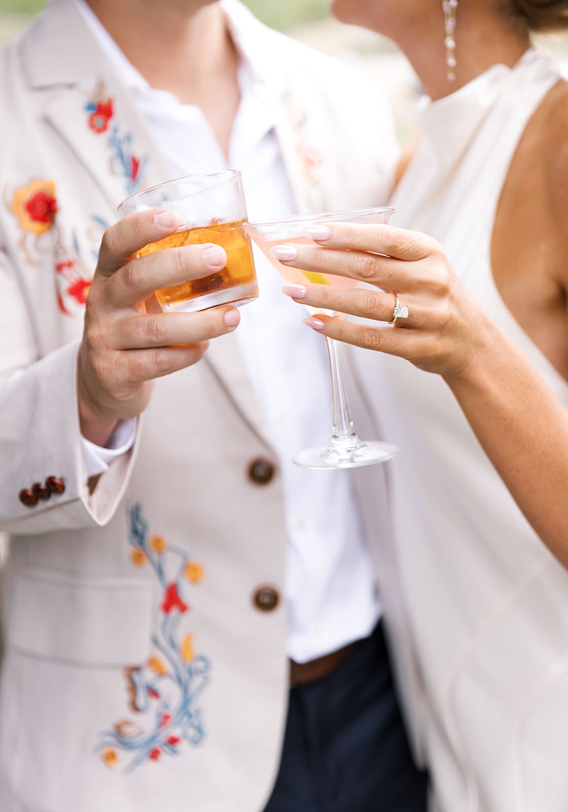 Couple toasting cocktails at their rehearsal dinner in stylish modern outfits