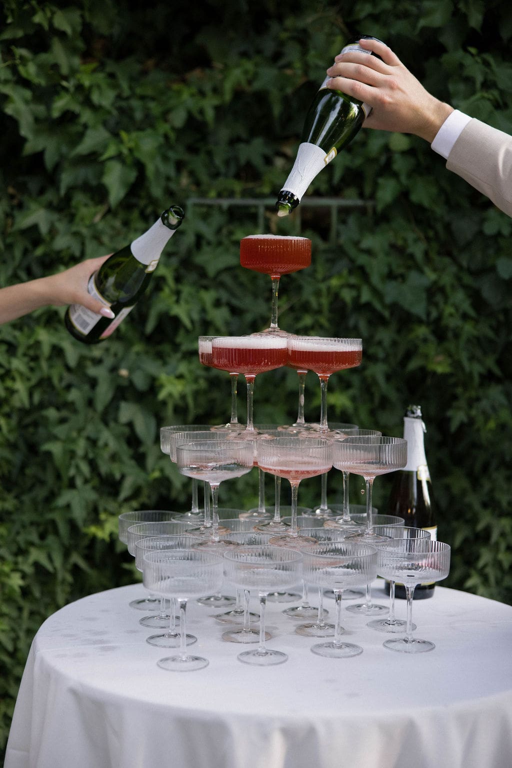 a tower of champagne glasses being filled with sparkling wine